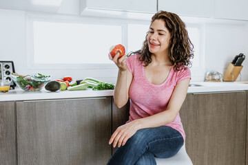 Wall Mural - Latin woman healthy eating in the kitchen at home in Mexico, Hispanic people wellbeing