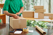 © DragonImages - Mail worker sealing cardboard boxes before shipping goods to customer