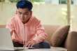 © DragonImages - Serious young man studying online watching webinars on laptop and taking notes