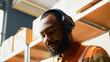 © DC Studio - Male employee listening to music and working in depot, having fun dancing and using tablet to plan inventory. Young adult singing with headphones, working on stock production shipment. Handheld shot.