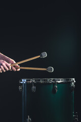 Wall Mural - A man plays a musical percussion instrument with sticks on a dark background.