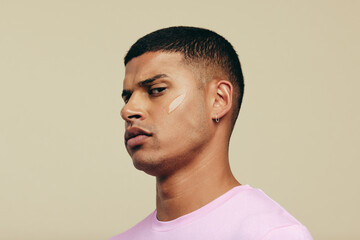 Wall Mural - Young man looking at the camera with skin serum on his face