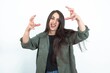 young brunette woman wearing casual clothes over white studio background Shouting frustrated with rage, hands trying to strangle, yelling mad.