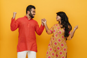 Wall Mural - Young indian woman and man laughing and clenching their fists isolated