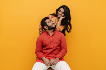 Wall Mural - Indian man and woman looking at each other while posing isolated over yellow background