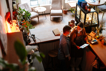 Wall Mural - Woman teaching man with down syndrome to use tablet during internship in cafe