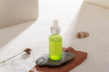 Wall Mural - Green cosmetic serum bottle on natural stones podium in sunlight. Front view, mockup