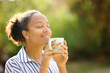 Leinwandbild Motiv Relaxed black woman smelling coffee in a park