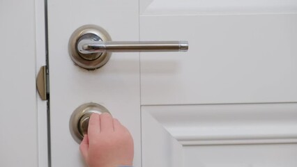 Wall Mural - Little baby opens the door. Child pulls the door handle with the lock closed. Kid aged about two years (one year nine months)