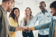 © Flamingo Images - Laughing team of diverse businesspeople standing with their hands together
