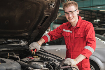 Auto mechanic working in garage, Technician man working in auto service, Technicians with charging cables for car battery, Car repair, and maintenance