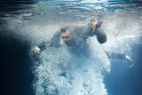 Fototapeta Łazienka - A businessman in a suit swims through the swirling current.