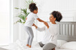 © JenkoAtaman - Happy ethnic family. African american kid jumping, play and laugh on bed with mom.