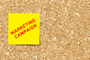 Sticker - Yellow note paper with word marketing campaign on cork board background with copy space