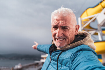 handsome middle aged man taking a selfie on the deck of a ship - Happy tourist traveling by cruise ship - Tourism and vacation concept