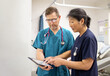© Austockphoto - Man and woman health care workers standing  while looking at a tablet in the clinic