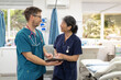 © Austockphoto - Smiling man and woman health care workers looking at echother while holding a tablet in the clinic