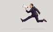 © Studio Romantic - Crazy funny man in suit and glasses isolated on light gray background jumping high in air, yelling through megaphone, making announcement, advertising vacancy, or drawing attention to urgent problem