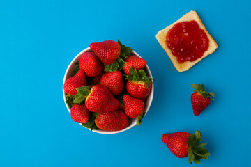 Wall Mural - A top view of the strawberry jam-filled bread and strawberry fruit isolated on blue