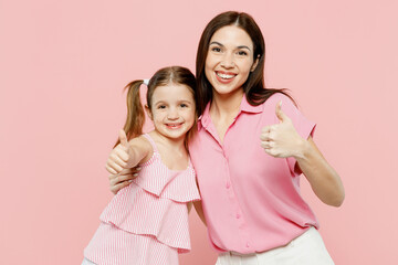 Wall Mural - Happy smiling cheerful woman wear casual clothes with child kid girl 6-7 years old. Mother daughter showing thumb up like gesture isolated on plain pastel pink background. Family parent day concept.