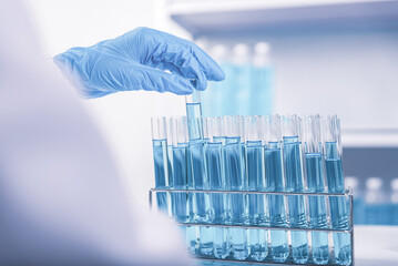 Wall Mural - chemist,scientist hand pick up test tube from rack in laboratory background, science research and de