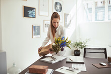 Smiling Woman Laying A Flower Bunch On Her Office Desk
