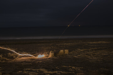 Wall Mural - An exploding firecracker on the sand against the background of the sea