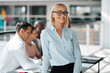 © Flamingo Images - Young businesswoman smiling with colleagues working in the background