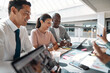 © Flamingo Images - Businesspeople laughing while working together in an office meeting area