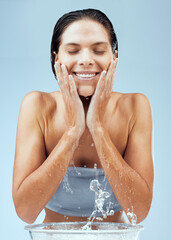 Wall Mural - Clean skin feels amazing. Studio shot of an attractive young woman washing her face against a blue background.