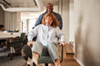 © Flamingo Images - Man pushing a coworker in an office chair