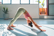 © ADDICTIVE STOCK - Focused woman performing Downward Facing Dog pose in studio