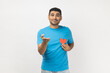 © khosrork - Portrait of falling in love romantic unshaven man wearing blue T- shirt standing giving his heart to his girlfriend, looking at camera, expressing gentle. Indoor studio shot isolated, gray background