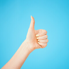 Now thats what I like. Studio shot of an unrecognisable woman showing thumbs up against a blue background.