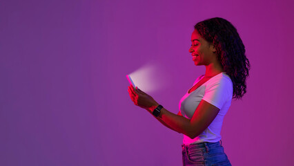 Online Gaming. Black Woman In Neon Light Looking At Glowing Smartphone Screen
