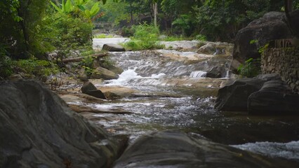 Wall Mural - waterfall stream and rocks on nature clear slow motion flow water with green trees jungle in natural garden rainforest at Phalad Waterfall Lan sang forest national park for summer landscape background