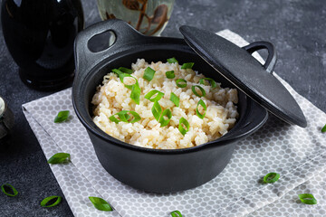 Wall Mural - Stewed rice with chicken in a pot on dark grey background