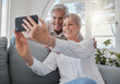 © K Davis/peopleimages.com - Enjoying their. an affectionate senior couple taking selfies while relaxing in the living room at home.