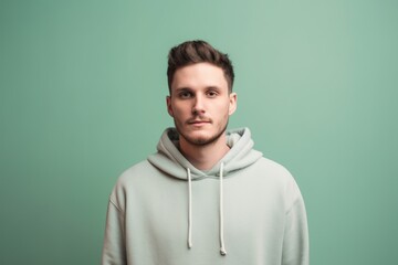 Wall Mural - Portrait of a young man in a green hoodie on a green background
