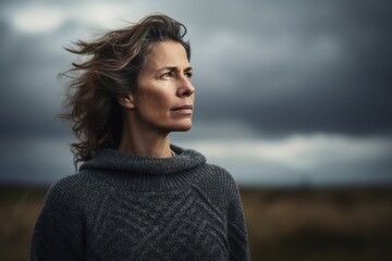 Sticker - Lifestyle portrait photography of a pleased woman in her 40s wearing a cozy sweater against a dramatic stormy sky background. Generative AI