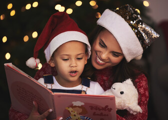 Canvas Print - Shes getting better by the day. a young mother and daughter reading a book during Christmas time at home.