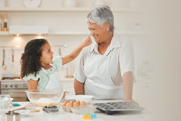 Sticker - My granddaughter makes me smile. a young girl playfully putting flour on her grandmothers nose during baking.