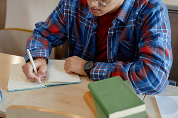 Wall Mural - High angle view of student making notes in notebook while sitting at desk during lecture