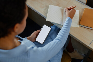 Wall Mural - High angle view of student sitting at desk and writing off the mobile phone in notebook during lecture