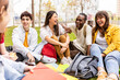 © Xavier Lorenzo - Young group of multiracial students laughing and having fun together sitting on the grass in the university campus. Teenage classmates social gathering relaxing outdoors.