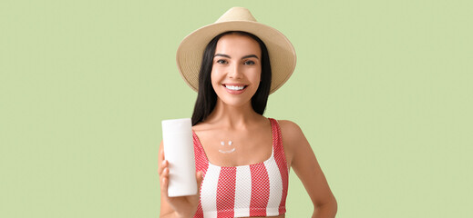 Sticker - Happy young woman with sunscreen cream on green background