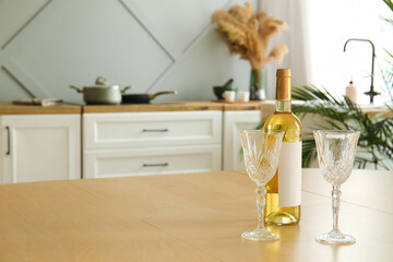 Bottle of wine and empty glasses on dining table in modern kitchen