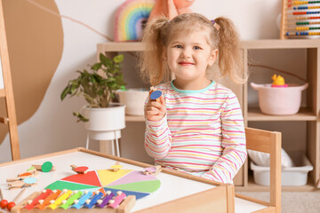 Wall Mural - Cute little girl playing matching game with clothespins at home