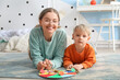 Cute little boy and his mother playing matching game with clothespins at home