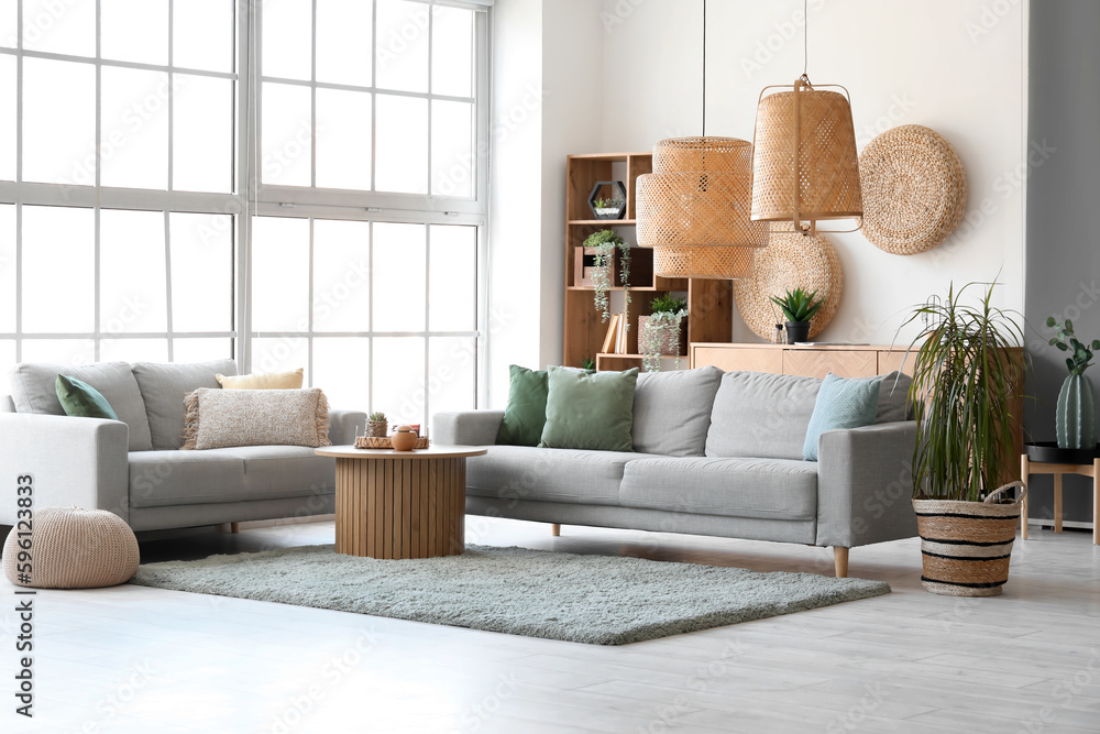 Interior of bright living room with cozy grey sofas and coffee table on soft carpet